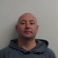 Photograph of Dylan Haldane - white man in 30s with shaved head and wearing grey hoodie.