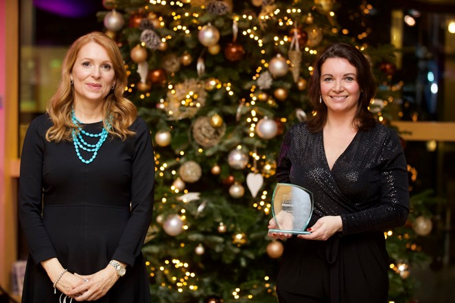 Minister for Community Safety, Ash Regan MSP, presents SWDF Chair Clare Hussain with the Scottish Public Sector Award for Championing Gender Equality. Both are standing in front of a decorated Christmas tree.