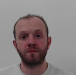 33-year-old white man with receding brown hair and facial hair. Wearing a white top