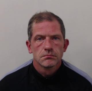 Robert McGregor - white man in 40s with thinning dark grey hair wearing dark-coloured long-sleeved shirt with a light blue stripe running along length of the arms and shoulders