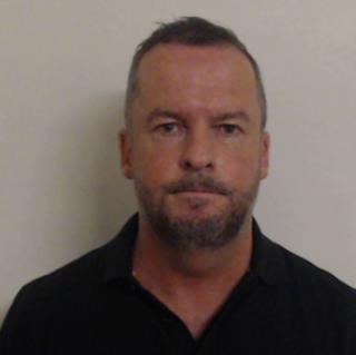 Picture of Andrew Polson - white man in 50s with short dark hair and stubbly beard wearing dark-coloured shirt