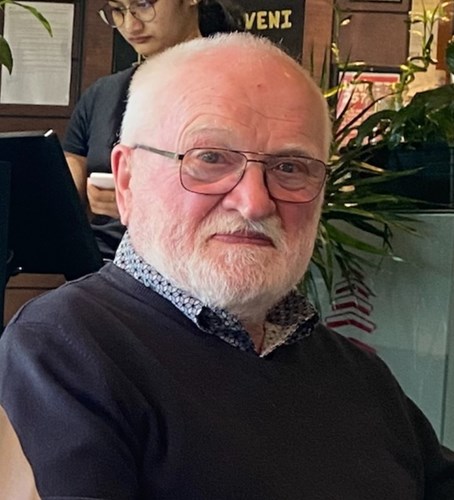 Missing person James Campbell, 82, with short grey hair, glasses and a short white beard. Sitting in a restaurant in front of a house plant
