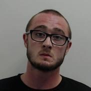 20-year-old man with short dark hair and beard. Wearing glasses and black top