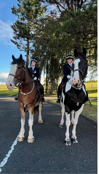 Two police horses with female officers sitting on each
