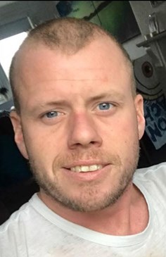 37-year-old man smiling at the camera wearing a white top