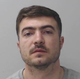 Image of Afrim Krasniqi - custody photo of white man in late twenties with short dark hair and dark stubbly beard wearing grey t-shirt