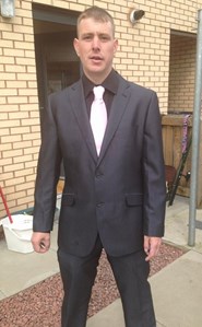 Image of Charles Wilson. A 43-year-old man with short brown hair wearing a dark coloured suit and shirt with light coloured tie.