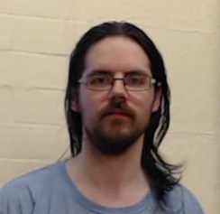 34-year-old white man with long, black hair and facial hair. Wearing glasses and a blue top