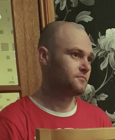 43-year-old man with shaved head wearing red top