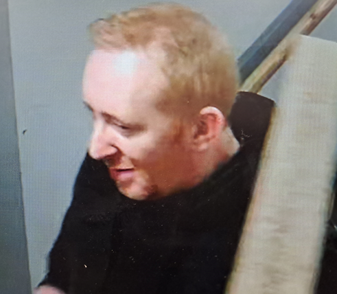 Side profile of man with short red/blond hair wearing a black hooded top