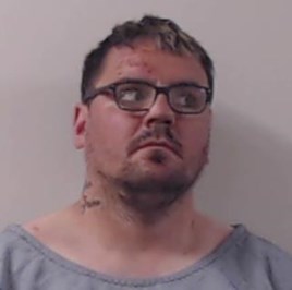 Image of jailed man Gordon Docherty - white man with large build. Short dark hair and stubble wearing grey t-shirt and dark framed glasses.